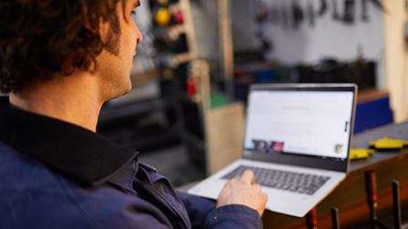 Een man zit achter zijn laptop.