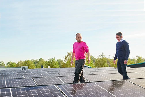De adviseur van Essent loopt met een ondernemer op een dak met zonnepanelen